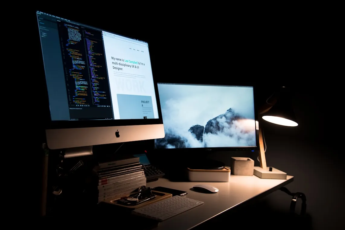 A desk setup with an iMac in a dark studio