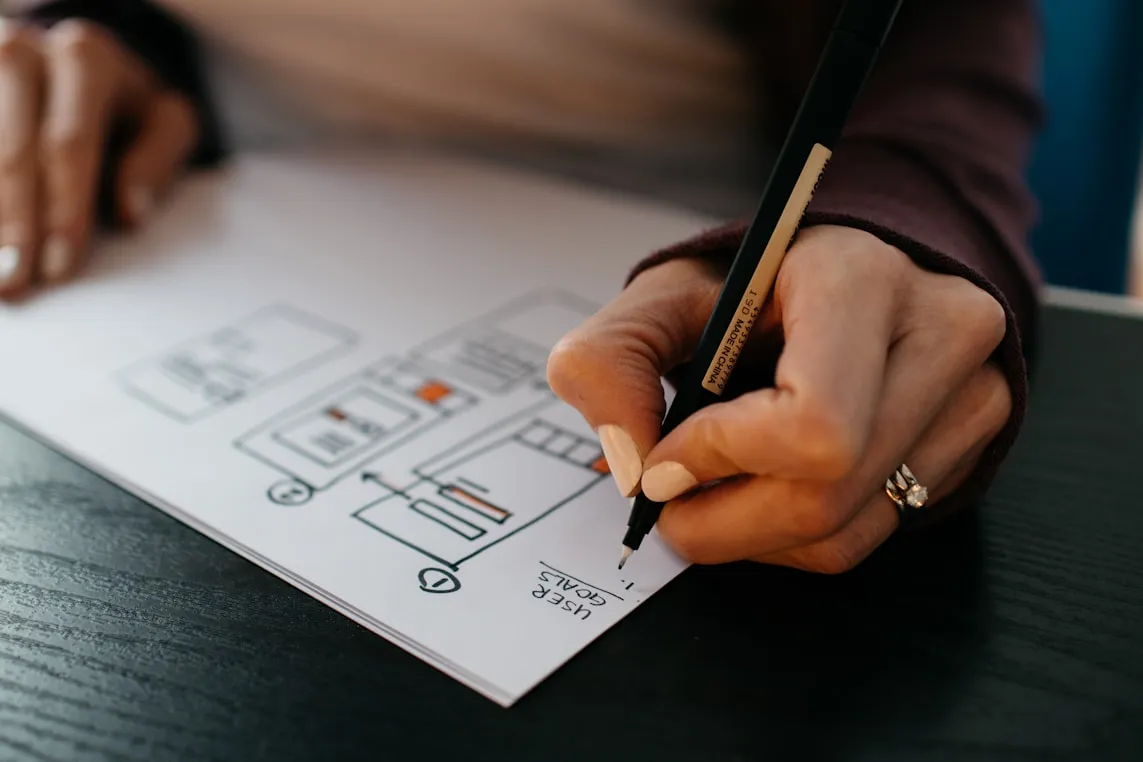 A hand sketching website wireframes on paper